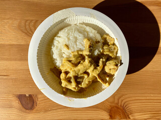 Take Away Rice with Curry Sauce Chicken in Plastic Bowl Plate Package Container on Wooden Table.