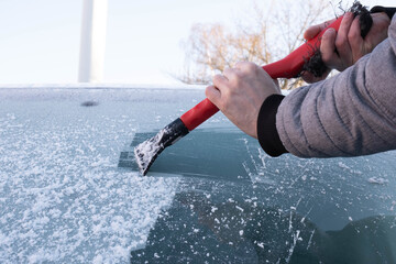 a man cleans the windshield of the car from ice