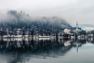 Fototapeta na wymiar View of Bled lake in the morning, Slovenia. Fog over the city and mountains
