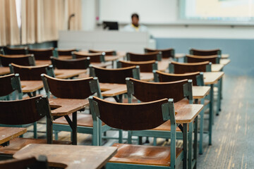 Wooden lecture chairs arranged in the classroom. Empty college classroom with many vintage wooden lecture chairs but no students. Back to school concept. 