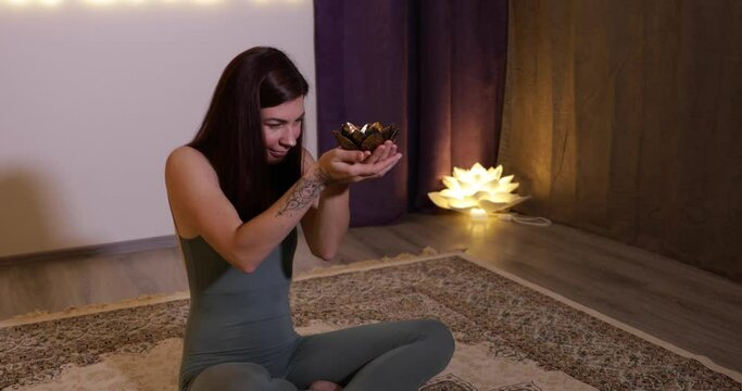 yogi woman sitting in lotus position and leaning her forehead against a candle