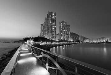 Seaside promenade and high rise residential building in Hong Kong city at dusk