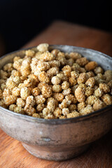 Dried white mulberry in white bowl over wooden background