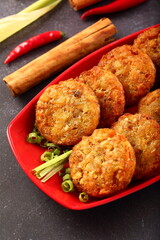 Crispy fried vegetarian cutlets served in red plate.