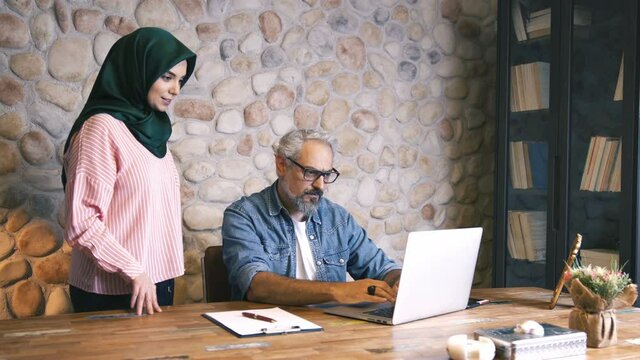 Male and muslim female business people working on a project at the office. Slow motion video.