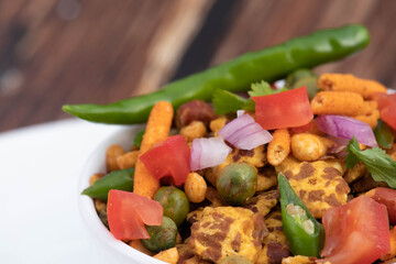 Mixed Assorted Spicy Indian Street Food Chatpata Namkeen Chana Jor Garam With Daal Boot Mixture Chopped Onions Cut Green Chilli Tomatoes Matar Served In White Bowl On Brown Wooden Texture Table