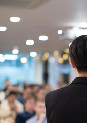 Speaker giving a talk at a corporate business conference.
Audience in hall with presenter in front of presentation screen. Corporate executive giving speech during business and entrepreneur seminar.