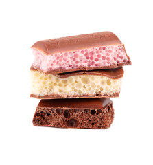 Mix of porous chocolate pieces isolated on white background. Black, white and pink aerated chocolate.