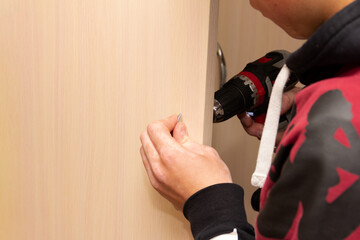 carpenter furniture maker screws the door handle to the door of the wardrobe
