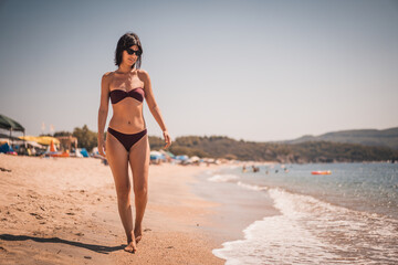 Young beautiful woman having fun at beach. Summer photo of young beautiful girl. Female on beach enjoying sea vacation traveling