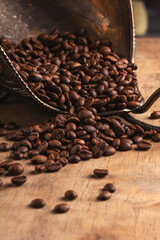 Coffee beans in a bronze bowl on a wooden background