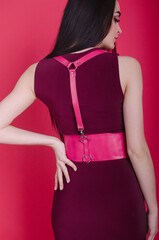 Young, beautiful girl in a leather port. Sexy leather accessory on a girl's clothes. Leather belts as clothing accessory