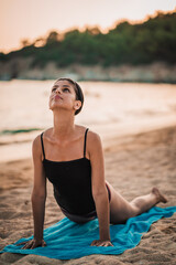 Young beautiful woman practicing pose from yoga on the beach at sunset. Female on beach exercising on vacation