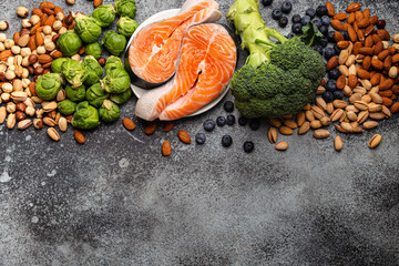Assorted food for brain health and good memory: fresh salmon, vegetables, nuts, berries on stone background. Healthy fresh products to boost brain power, top view with space for text

