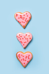 Valentines day vertical greeting card with three glazed heart shaped cookies on blue.