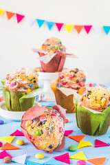 Colourful muffins on blue, decorated with a party garland and chocolate beans for a party, birthday, carnival, new year. Vertical.