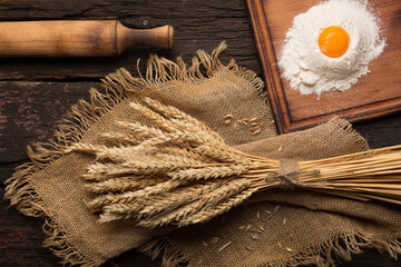 Fototapeta na wymiar Bread baking bakery concept. Eggs, flour, spikelets on a wooden antique table. close up
