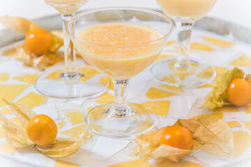 Glass with eggnog and physalis fruits on a round tray