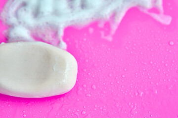 Washing concept. Foam bubbles and brick of soap on pink background. Cleaning service