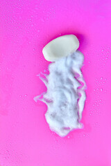 Washing concept. Foam bubbles and brick of soap on pink background. Cleaning service