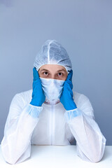 man in protective suit, gloves and mask on his face holding his head pretending to panic or fear. The concept of health.