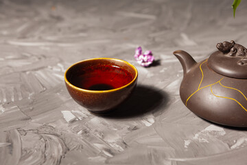 Chinese tea. Tea bowl and teapot on a dark background. Lilac flowers in a vase