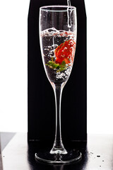 Filling up the champagne glass with strawberry isolated on a black background copy space
