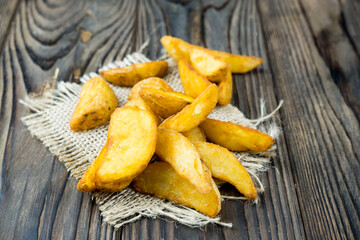 potatoes cooked in a rustic way. delicious potato slices on a wooden table.