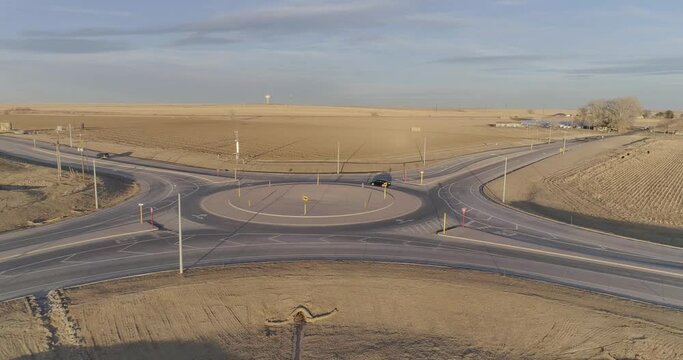 A modern roundabout in the middle of nowhere,  Cars navigate a circle.