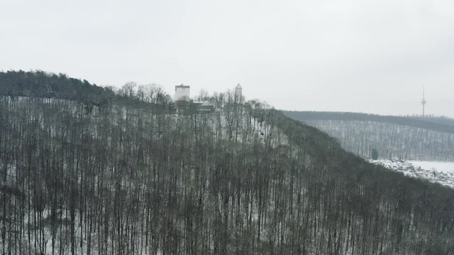 Drone aerial of the fairy tale castle Plesse in winter with a huge amount of snow on a beautiful mountain near Bovenden, Germany, Europe.