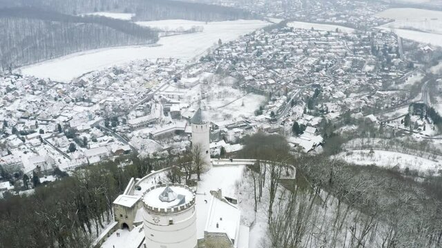 Drone aerial of the fairy tale castle Plesse in winter with a huge amount of snow on a beautiful mountain near Bovenden, Germany, Europe.