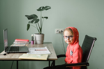 Little girl in eyelgasses having online lesson at home