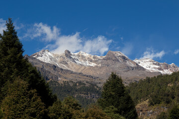Fototapeta premium Landscape of the Iztaccihuatl Mountain covered in greenery under a blue sky in Mexico