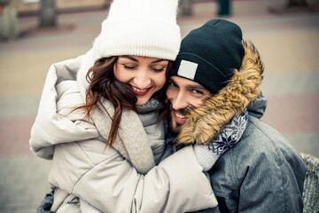 Young lovely couple bride groom newlyweds sitting street kissing hugging, spending time together, smiling happy joke. New Year Christmas decorations, Valentines Day concept.