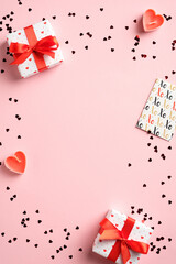 Valentines Day vertical banner template with gift boxes, candles, greeting card, confetti on pink background. Flat lay, top view.