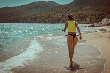 Young beautiful woman having fun in water at beach. Summer photo of young beautiful girl in sea swimming and having fun. Female on beach enjoying sea vacation traveling