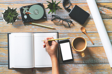 Office desk table with computer keyboard,coffee,glasses and hand writing on blank notebook. Top...