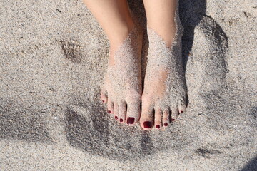 mujer con los pies llenos de arena en la orilla de la playa