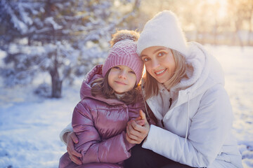 Mother and daughter having fun in the winter park.