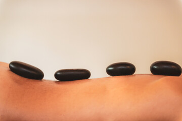 Fototapeta na wymiar Young woman having beauty treatment with hot stones massage in a spa salon.