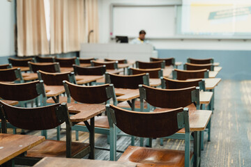 Wooden lecture chairs arranged in the classroom. Empty college classroom with many vintage wooden lecture chairs but no students. Back to school concept. 