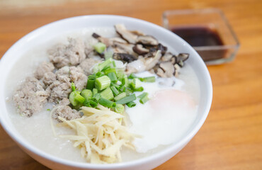 Pork porridge with eggs placed on a wooden table.