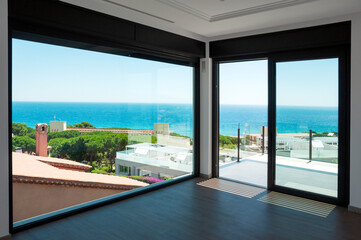Fototapeta na wymiar Empty room with large panoramic windows overlooking the sea. Room after major renovation. 
