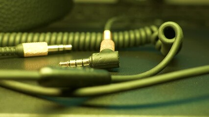 Music, stereo 3.5 mm cable on table in changing color led lamp lighting - Powered by Adobe