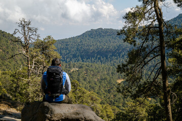 A male hiker with a backpack sitting on a rock on the Iztaccihuatl Mountain in Mexico
