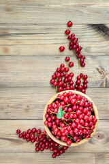 Red currant in a bowl on wooden background. Top view, copy space.