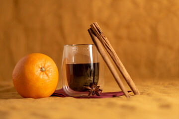 roter Glühwein mit Orange und Zimtstangen (oranger Hintergrund)