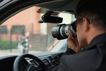 Fototapeta Private detective with camera spying from car obraz