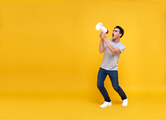 Fototapeta na wymiar Young Asian man shouting into megaphone making announcement in isolated on yellow background.
