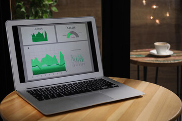 Modern laptop with diagrams on table in cafe